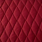 Protector de colchón acolchado en microfibra color rojo vino, mostrando el patrón de costuras diagonales en forma de rombos.