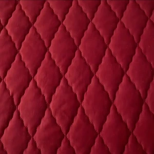 Protector de colchón acolchado en microfibra color rojo vino, mostrando el patrón de costuras diagonales en forma de rombos.