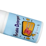 Frasco de quitamanchas portátil de 50 mL con etiqueta azul claro. La etiqueta ilustra una camiseta rosa con una mancha amarilla siendo limpiada, destacando la eliminación inmediata de manchas sin lavado.