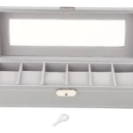 Relojero X6 gris claro con cristal transparente y llave incluida, abierto mostrando seis compartimentos acolchados para almacenamiento seguro.