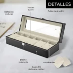 Relojero negro de cuero PU con tapa de vidrio, abierto y mostrando seis compartimentos acolchados para relojes de hasta 42 mm. Incluye broche resistente y almohadillas suaves.