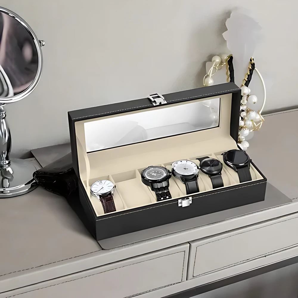 Relojero negro con tapa de vidrio, abierto y mostrando seis relojes de pulsera en compartimentos individuales sobre superficie clara.