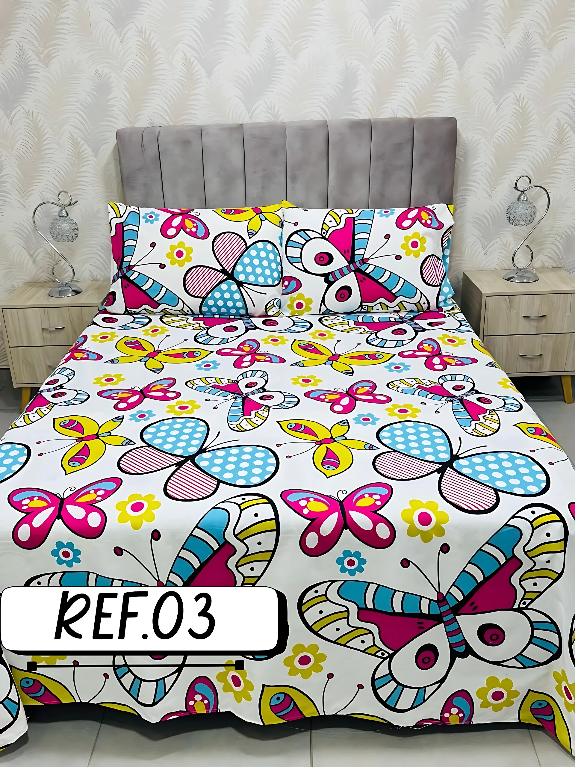 Sábanas dobles blancas con estampado de mariposas y flores en colores vibrantes, textura suave.