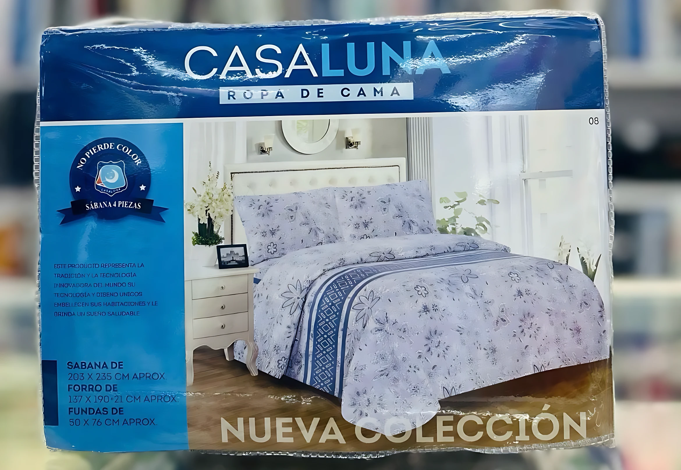 Juego de sábanas 4 piezas Casaluna en empaque. Diseño floral en tonos lavanda y azul con franja geométrica. Medidas visibles: sabana 203 x 235 cm.
