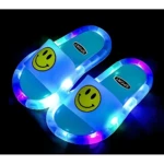 Sandalias luminosas antideslizantes para niños, con diseño de cara sonriente amarilla y luces multicolores en la suela.