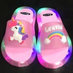Sandalia luminosa rosa para niños con unicornio y arcoíris, suela LED multicolor y diseño antideslizante.