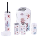 Set de seis accesorios de baño con diseño marino: escoba, papelera, dos frascos, dos vasos y tapa, todos en blanco con estampado de estrellas de mar y corales.