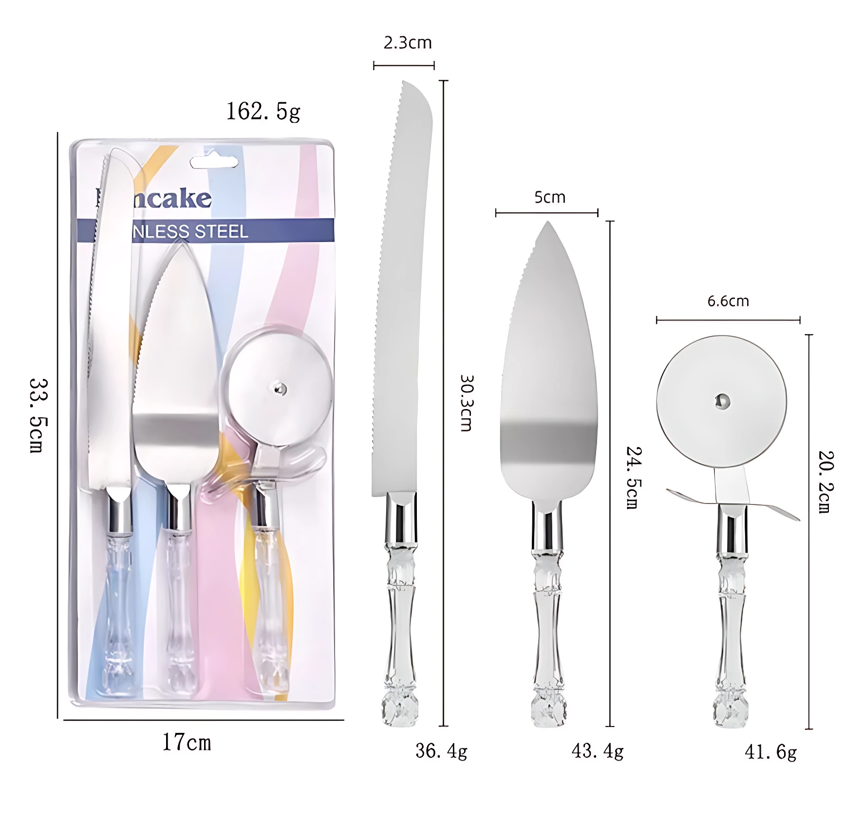 Set de tres utensilios de cocina en empaque: cuchillo de torta con hoja dentada, espátula de servir y rodillo para pizza, todos con mango acrílico transparente y detalles metálicos. Medidas visibles: 33.5 cm de altura total, 17 cm de ancho del empaque, 2.3 cm de grosor de hoja, 5 cm de ancho de espátula, 6.6 cm de diámetro del rodillo. Peso total: 162.5 g.