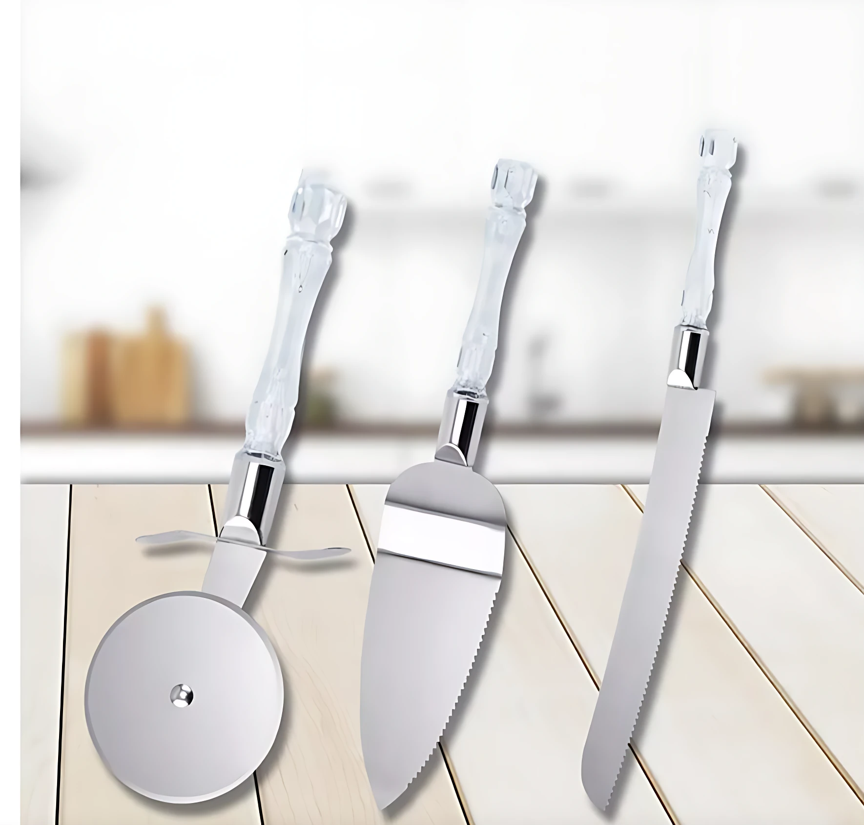 Set de tres utensilios de cocina con mango acrílico transparente: rodillo para pizza, espátula para servir y cuchillo serrado, sobre superficie de madera clara.