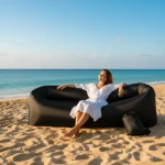 Sofá inflable portátil negro de nylon ripstop en playa, mujer relajada.