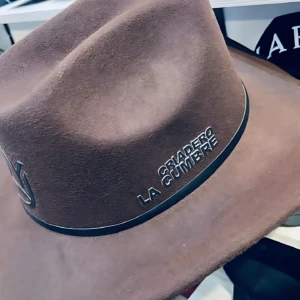 Sombrero café de algodón con estampado "Criadero La Cumbre" y banda negra, estilo Yeison Jiménez.