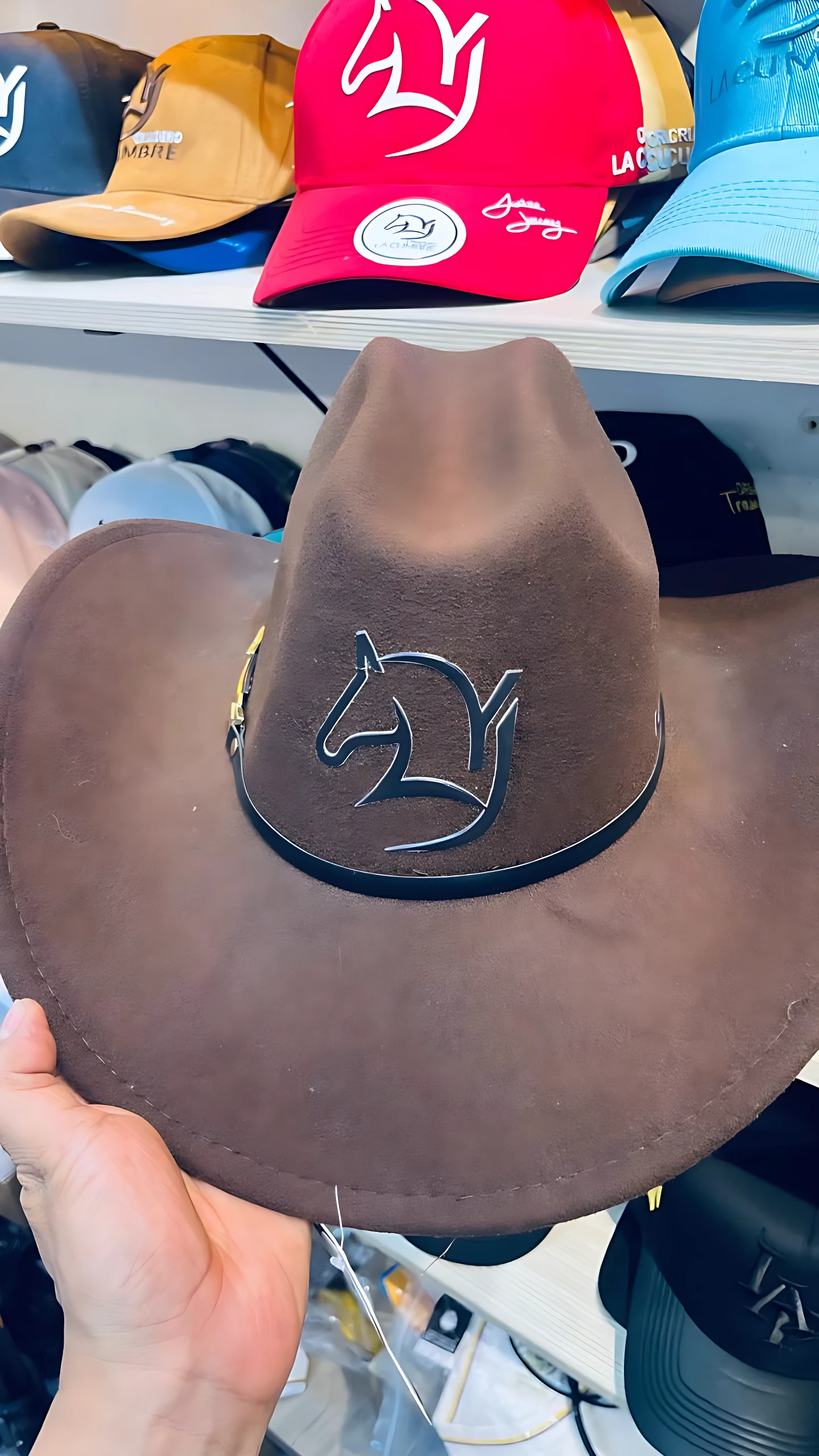 Sombrero café estilo vaquero con estampado de caballo, banda negra y hebilla dorada.