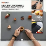 Tapete de cocina gris multifuncional con accesorios decorativos y manos trabajando sobre su superficie, mostrando uso en cocina y manualidades.