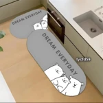 Tapetes absorbentes grises con diseño de ositos y frase Dream Everyday, uno largo y otro pequeño, colocados en cocina junto a fregadero y horno.