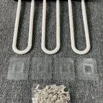 Tendedero plegable de plástico blanco con cinco ganchos en forma de U, acompañado de cuatro adhesivos y un paquete de clips de sujeción, sobre superficie texturizada gris.