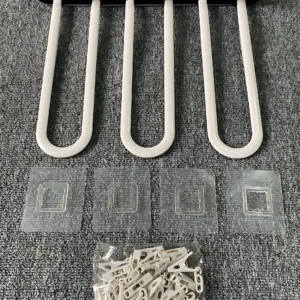 Tendedero plegable de plástico blanco con cinco ganchos en forma de U, acompañado de cuatro adhesivos y un paquete de clips de sujeción, sobre superficie texturizada gris.