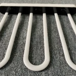 Tendedero plegable de plástico blanco con cinco ganchos negros, sobre superficie gris texturizada.