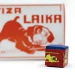 Cubo de tiza Laika para billar, color rojo con diseño de perro amarillo y tapa azul, junto a su caja con del mismo perro y texto Tiza Laika.