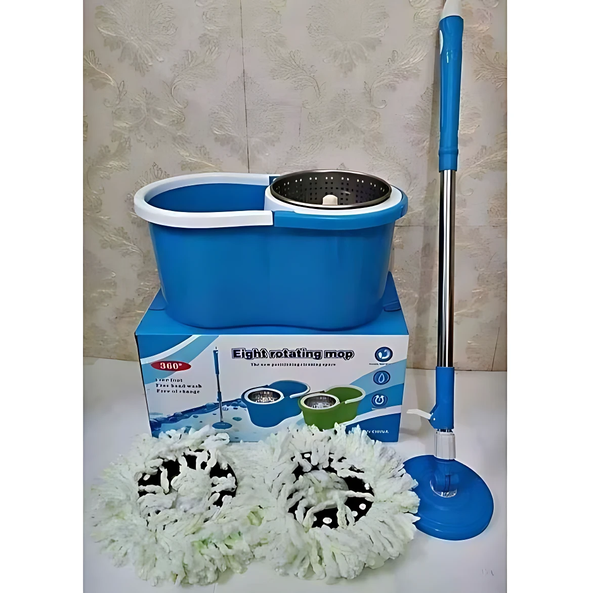 Trapero giratorio azul con tambor metálico, mopa blanca enrollada y caja de presentación; incluye mango telescópico y base de exprimido.