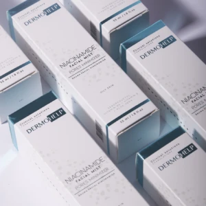 Caja de bruma facial Niacinamida de Dermhelp, presentación blanca con detalles en azul claro, dispuesta en diagonal sobre fondo blanco.