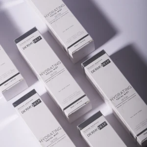 Seis cajas blancas del producto Bruma Ácido Hialurónico con Té Verde y Café, dispuestas en diagonal sobre fondo blanco, mostrando claramente la etiqueta frontal con el nombre del producto y detalles de hidratación profunda y detox sin grasa.