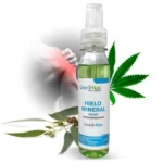 Botella transparente de 120 ml de spray Hielo Mineral Sport de Live Nat, con líquido verde claro, etiqueta blanca y azul, acompañado de hojas de cannabis y eucalipto, y mano señalando zona de dolor.