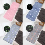 Cuatro alfombras felpudo luminosas con diseños temáticos: lunas y estrellas verdes, cielo nocturno azul, patrones de animales y deportes, todas sobre cama con sábanas blancas y mantas grises.