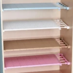 Cuatro repisas expandibles ajustables en tonos azul, blanco, beige y rosa, instaladas horizontalmente dentro de un armario de madera clara.