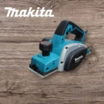 Cepillo eléctrico Makita KP0800 en color azul turquesa con detalles negros y gris, sobre superficie de madera texturizada.