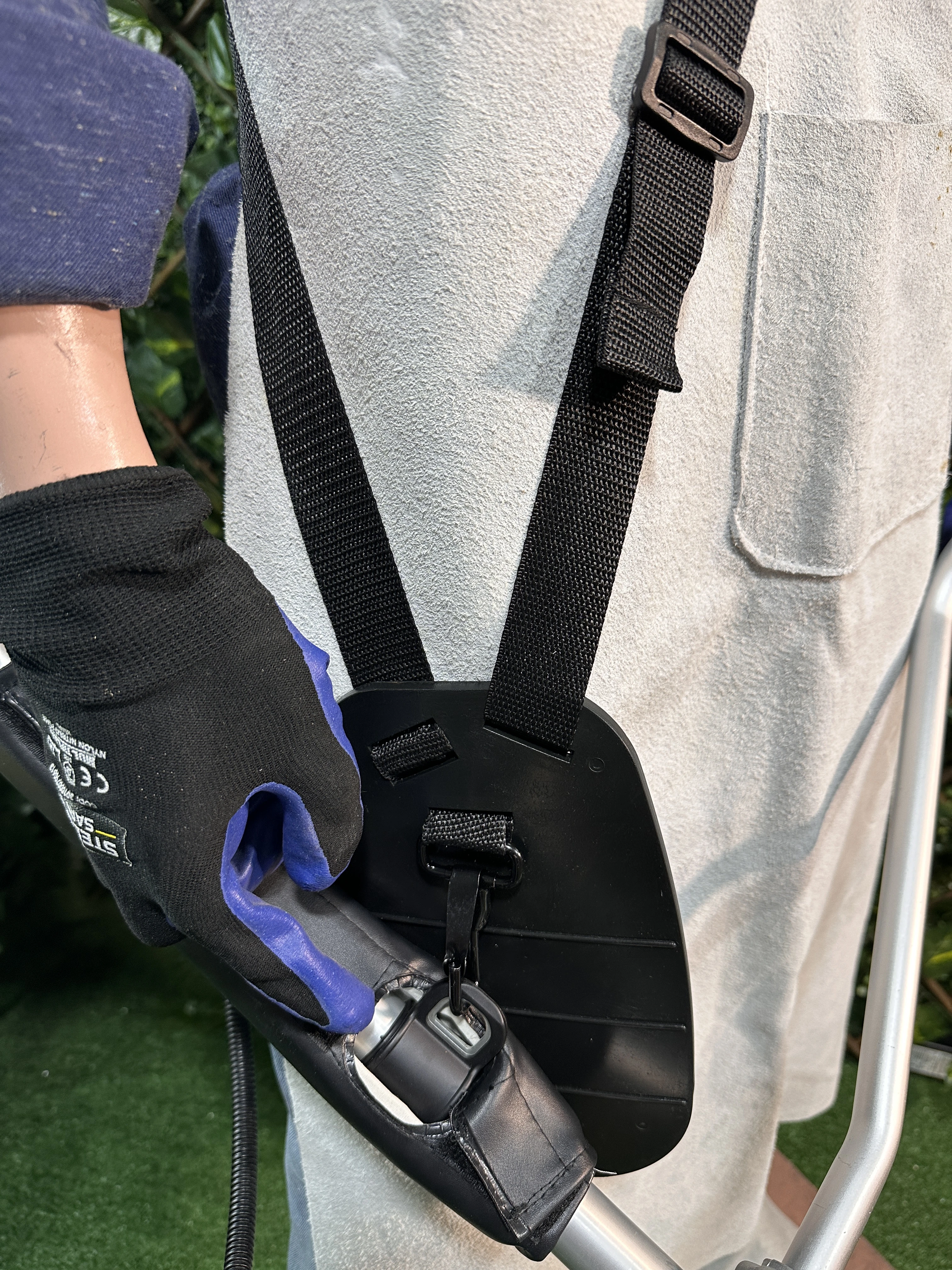 Kit de protección integral para carnaza en uso, con chaleco gris y guantes negros con detalles azules, mostrando sistema de correas y soporte de brazo.