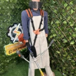 Maniquí con kit de protección integral para carnaza, incluyendo delantal beige, arnés naranja, casco amarillo con visera y guantes negros, sobre fondo verde artificial con logo Agrotecnia.