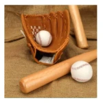 Guante de béisbol de cuero sintético reforzado en tono marrón, con pelota blanca dentro y dos bateas de madera a los lados, sobre fondo de lona texturizada.
