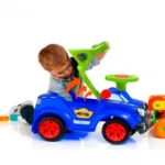 Niño pequeño montado en carro paseador azul con ruedas rojas y volante verde, diseñado para fomentar motricidad y equilibrio en etapa de aprendizaje.