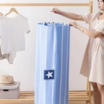 Mujer sosteniendo tendedero espiral azul con estrellas, colgado en perchero de madera; secado de sábanas sin arrugas.