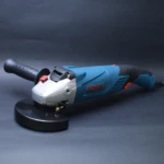 Pulidora angular Bosch de 125 mm, cuerpo azul con mango ergonómico negro y disco de corte montado, vista lateral sobre fondo gris oscuro.