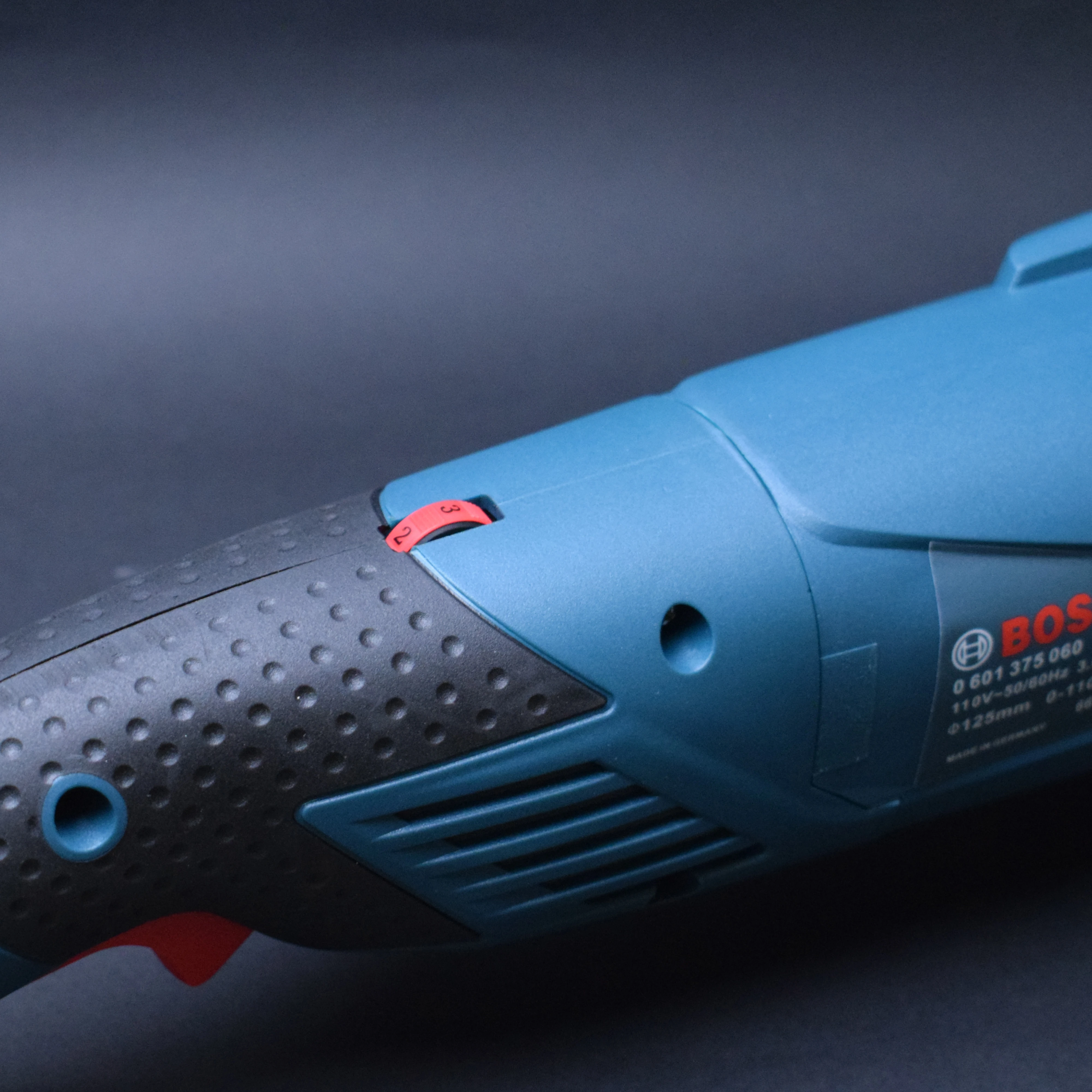 Pulidora profesional Bosch de 125 mm en azul y negro, con mango antideslizante texturizado y interruptor rojo visible, diseñada para eliminar óxido y pulir superficies.