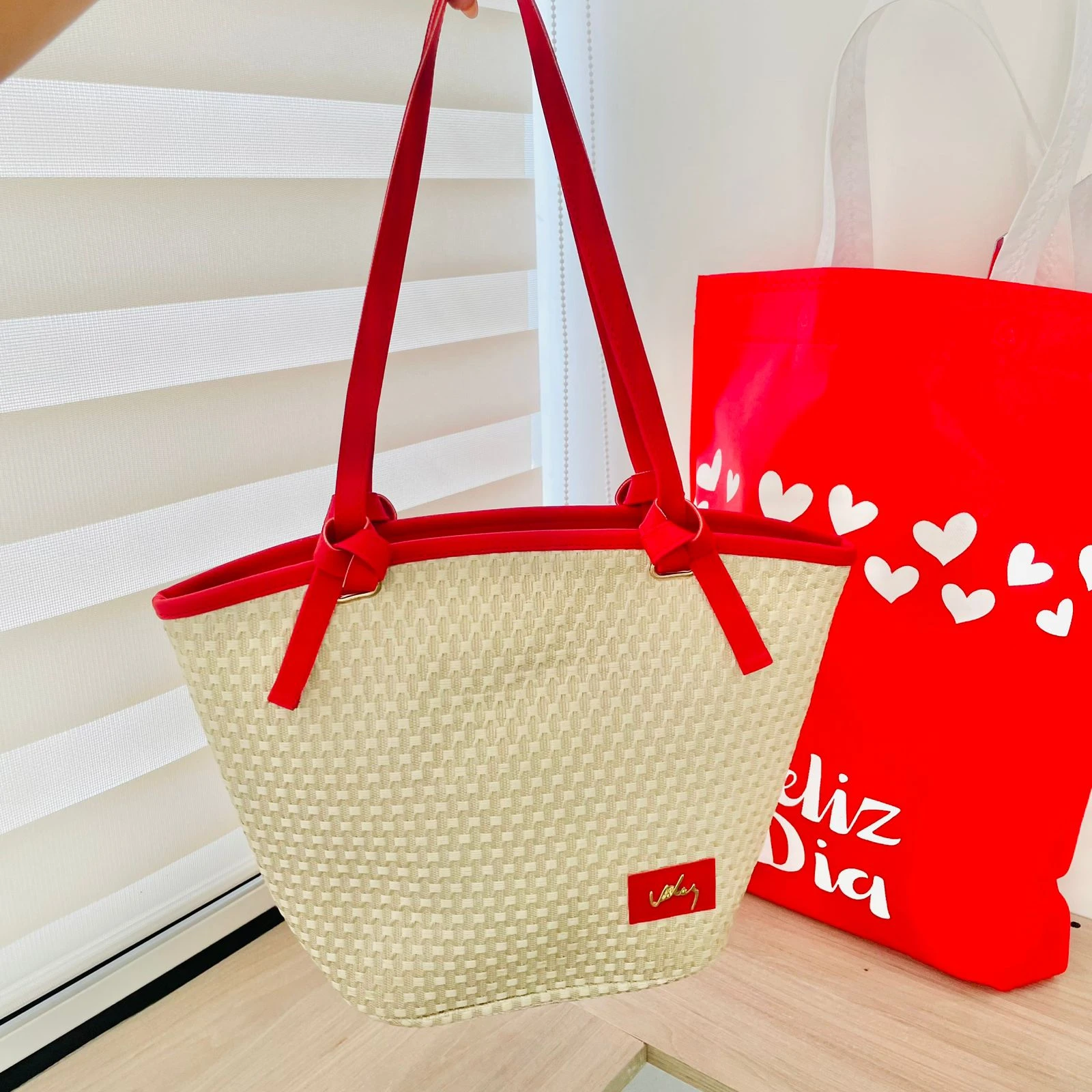 Bolso de mano tejido en yute natural con asas rojas y detalles en color rojo vivo, ideal para llevar compras frescas.
