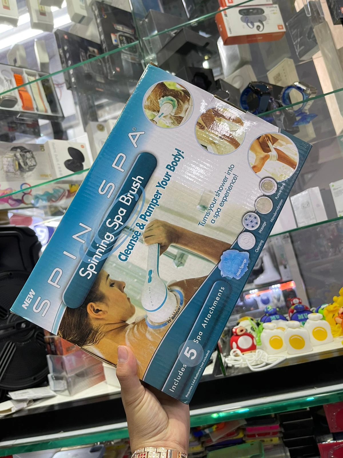 Cepillo eléctrico para ducha con cabezales giratorios, en caja azul mostrando uso y accesorios incluidos.