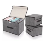 Tres cajas organizadoras de tela gris con tapa y cierre de velcro. Una abierta mostrando ropa doblada dentro; las otras dos cerradas apiladas.