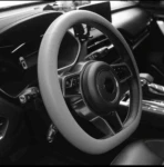 Volante de coche con forro de silicona antideslizante en tono gris claro, instalado en interior de vehículo, con detalles de textura y agarre mejorado.