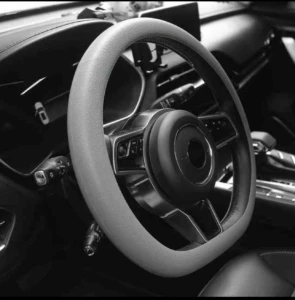 Volante de coche con forro de silicona antideslizante en tono gris claro, instalado en interior de vehículo, con detalles de textura y agarre mejorado.