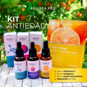Kit antiedad Serux+ con Vitamina C y ácido hialurónico. Incluye tres serums de 30 ml en frascos de vidrio oscuro con gotero, cajas correspondientes y mascarilla facial en envase amarillo con diseño de naranja. Presentación completa sobre superficie de madera clara, fondo con follaje verde y frutos naranjas.