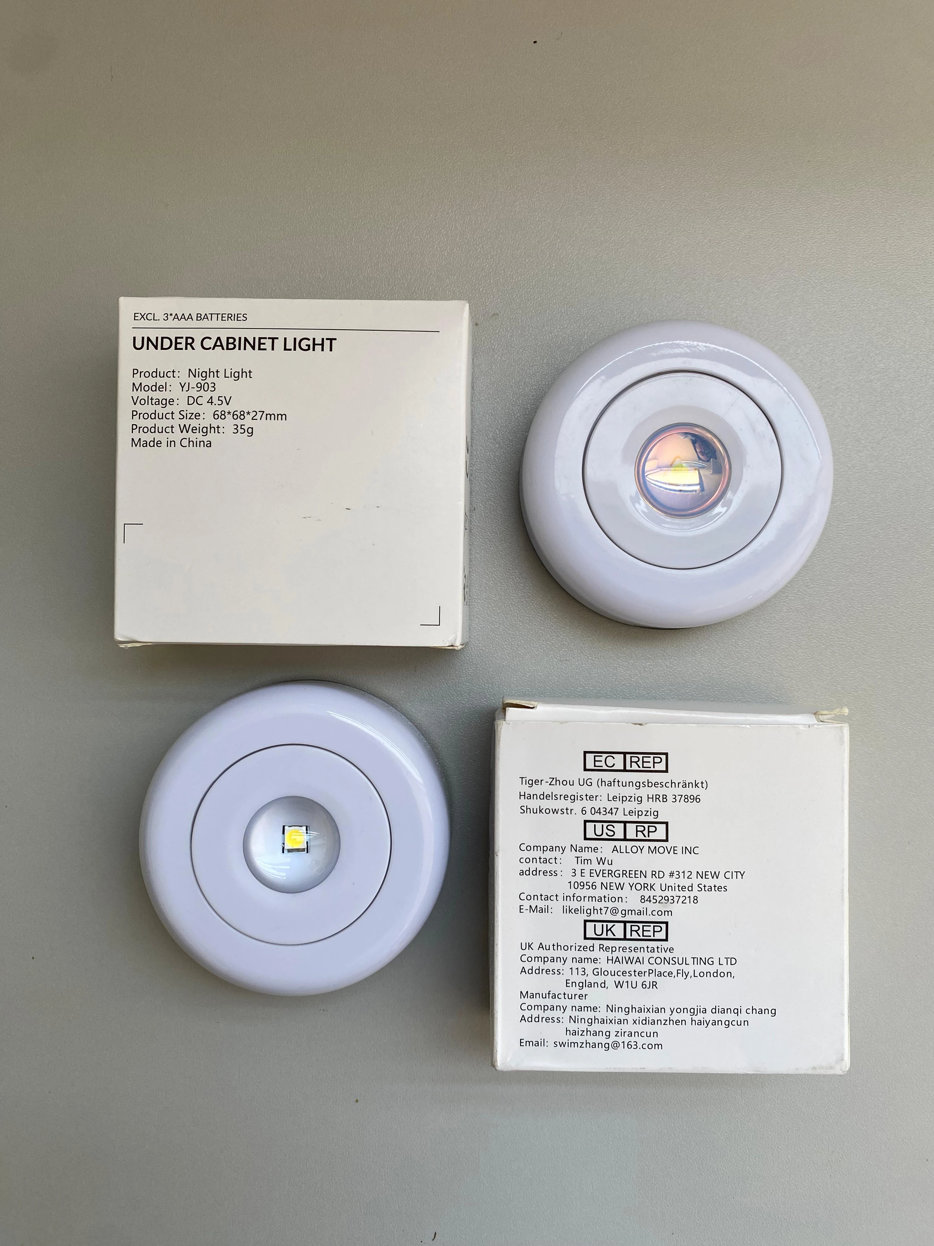 Set de dos lámparas LED circulares blancas con batería, modelo Night Light, junto a sus cajas de cartón con especificaciones técnicas visibles.