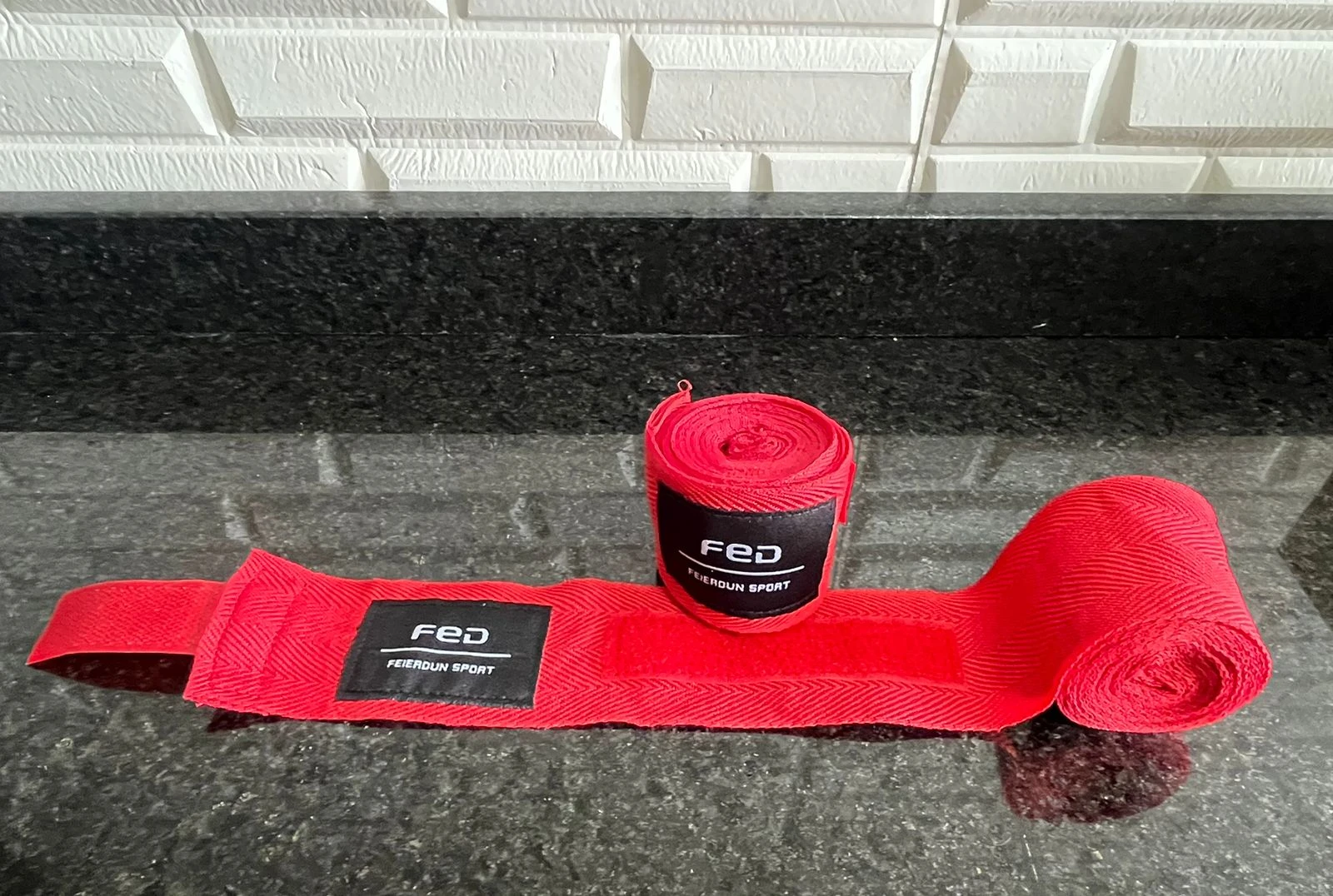 Vendas rojas para boxeo de la marca FED, enrolladas y extendidas sobre superficie oscura, con etiqueta visible.