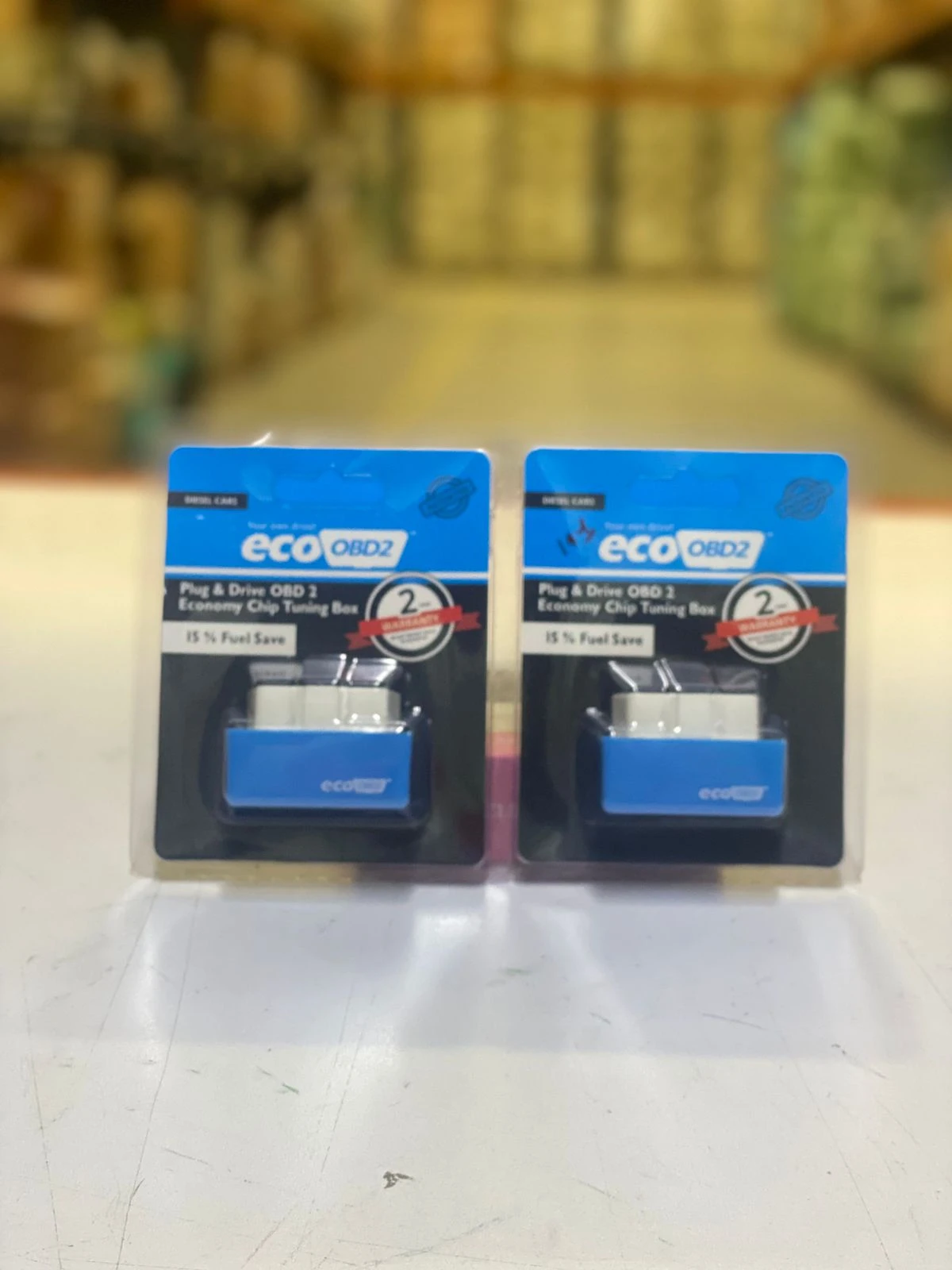 Pack de dos ahorradores de combustible para auto diésel, modelo Eco OBD2, en presentación individual con etiqueta azul y texto blanco.