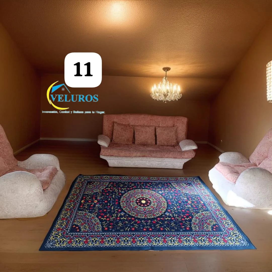 Alfombra persa de 2x1,50m con base antideslizante, diseño tradicional en tonos azules y rojos sobre fondo oscuro, colocada en sala de estar con sofá y sillones.