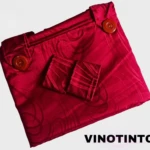 Cortina persa en tela jacquard color vino tinto, con botones decorativos y patrón floral sutil, vista frontal plegada.