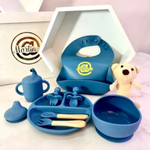 Juego de vajilla azul para bebé con biberón, plato dividido, bowl, chupete y babero; incluye osito de peluche y caja con logo Martine.