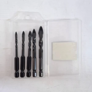 Pack de cuatro brocas multipropósito negras para vidrio y cerámica, con punta de corte y base hexagonal, presentadas en estuche transparente junto a una almohadilla adhesiva.