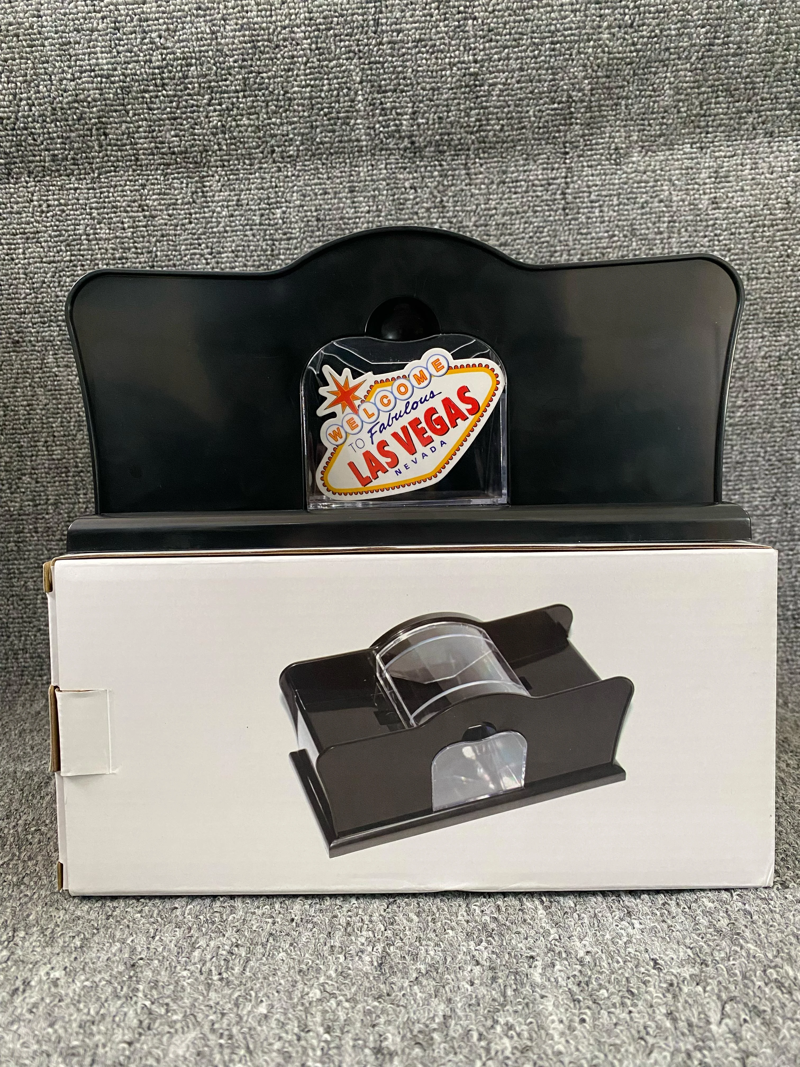 Barajador manual mecánico negro con base blanca, mostrando el dispositivo en uso sobre su caja de presentación.